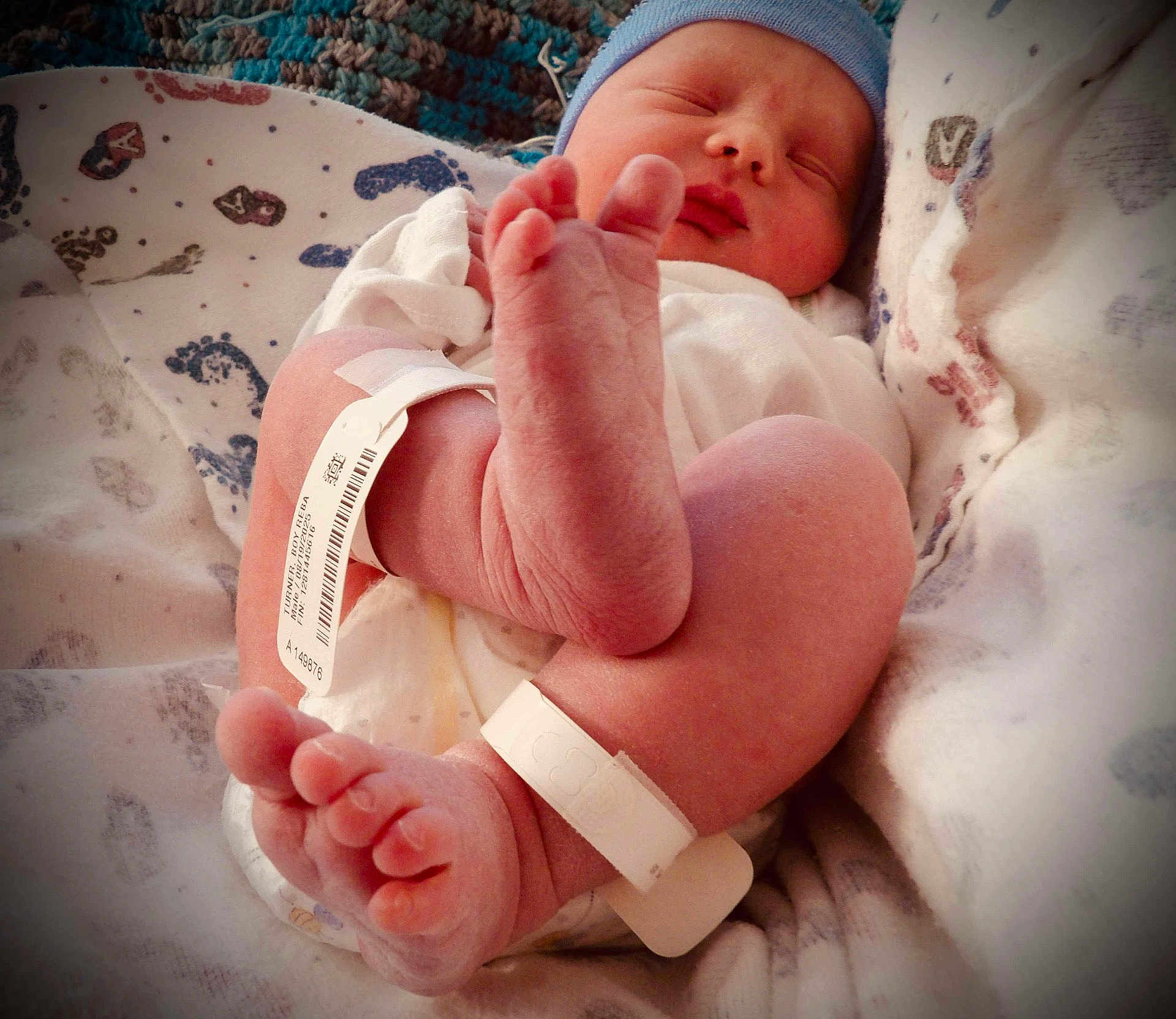 Davian is registered to the contest to win money with this photo: newborn, baby, infant, sleeping, feet, hospital, blanket, cap, id_band, cozy, cute, skin, foot, hospital_clothing, wrapped, peaceful, resting, human, child, soft