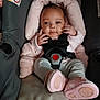 baby, infant, child, car_seat, harness, buckle, pink, booties, onesie, hands, face, headrest, cushion, warning_label, seat, portrait, cute, smile, clothing, indoors
