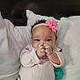 Niecey is registered to the contest to win money with this photo: baby, infant, headband, pink_flower, pillow, bed, blanket, smile, hands, pacifier, onesie, patterned_pants, cute, portrait, indoors, closeup, eyes, chubby_cheeks, skin, relaxed