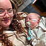 Hunter is registered to the contest to win money with this photo: woman, baby, pacifier, glasses, curly_hair, smile, sleeping, indoor, clothing, medical_tape, young_adult, child, face, person, holding, closeup, warm_light, background_blur, cozy, portrait
