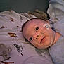 animal_print, baby, bed, blue_clothing, child, cute, expression, face, indoors, infant, lying_down, medical_device, nasal_cannula, pacifier, person, plush_toy, sheet, skin, smile, young