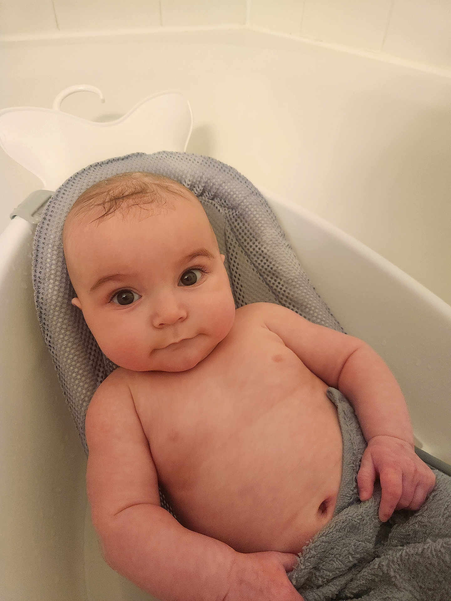 Ryan is registered to the contest to win money with this photo: arm, baby, bath, bathroom, bathtub, child, chubby, cute, expression, eyes, face, hand, indoors, infant, person, relaxing, seat, skin, towel, water