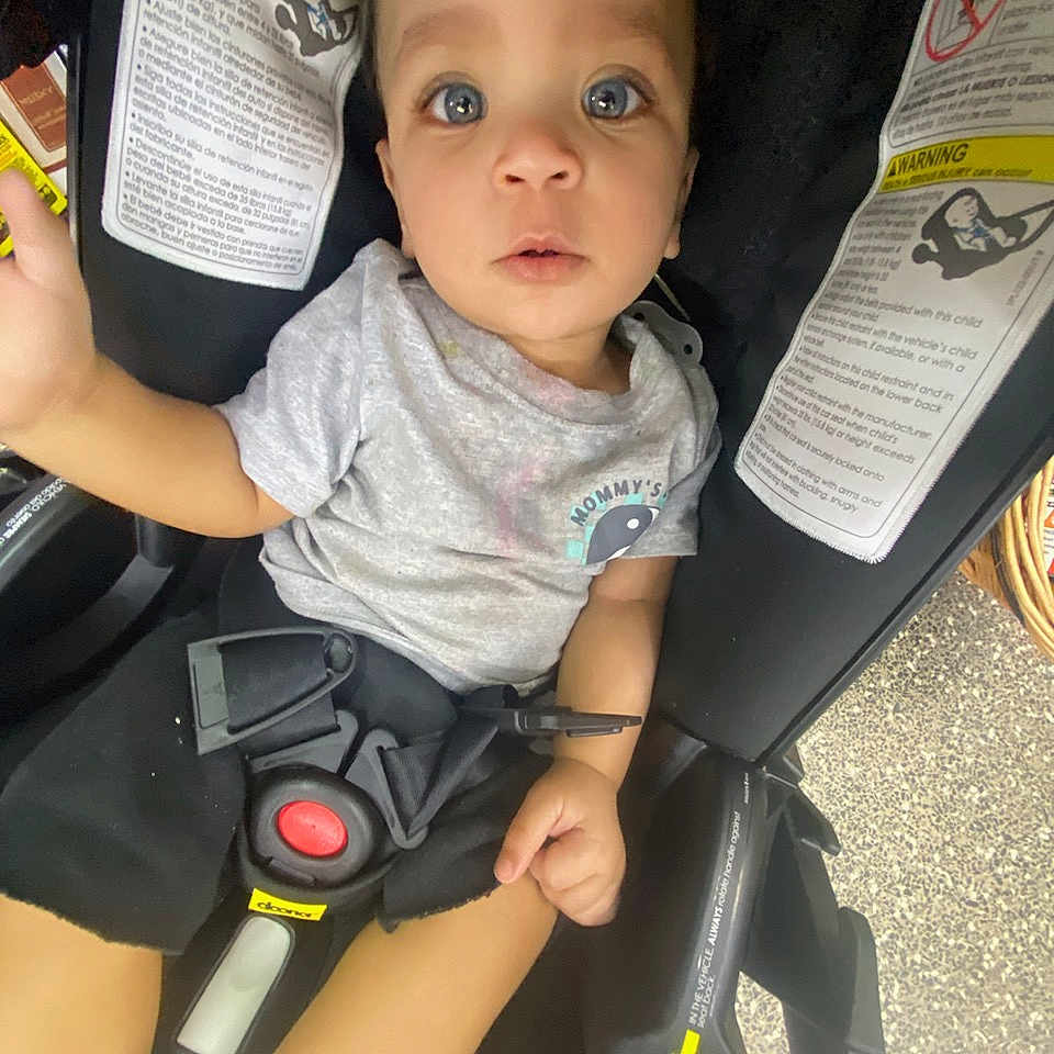 Allistaire Jr. is registered to the contest to win money with this photo: accessories, baby, belt, bodypart, car, car_interior, carseat, clothing, face, finger, head, person, photography, portrait, selfie, shorts, stroller, t_shirt, transportation, vehicle