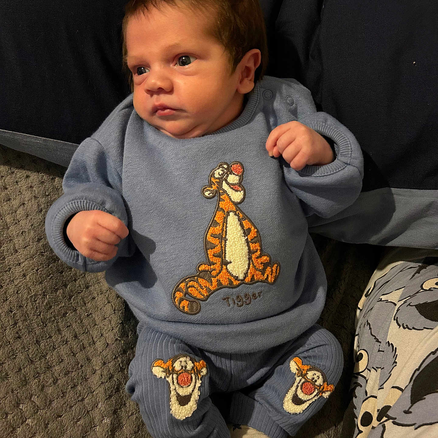 Theo joined the competition — help win amazing prizes! baby, blue_clothing, cartoon_character, child, closeup, cute, expression, fabric, face, indoor, infant, lying_down, pattern, patterned_socks, person, socks, soft_lighting, textile, texture, tigger
