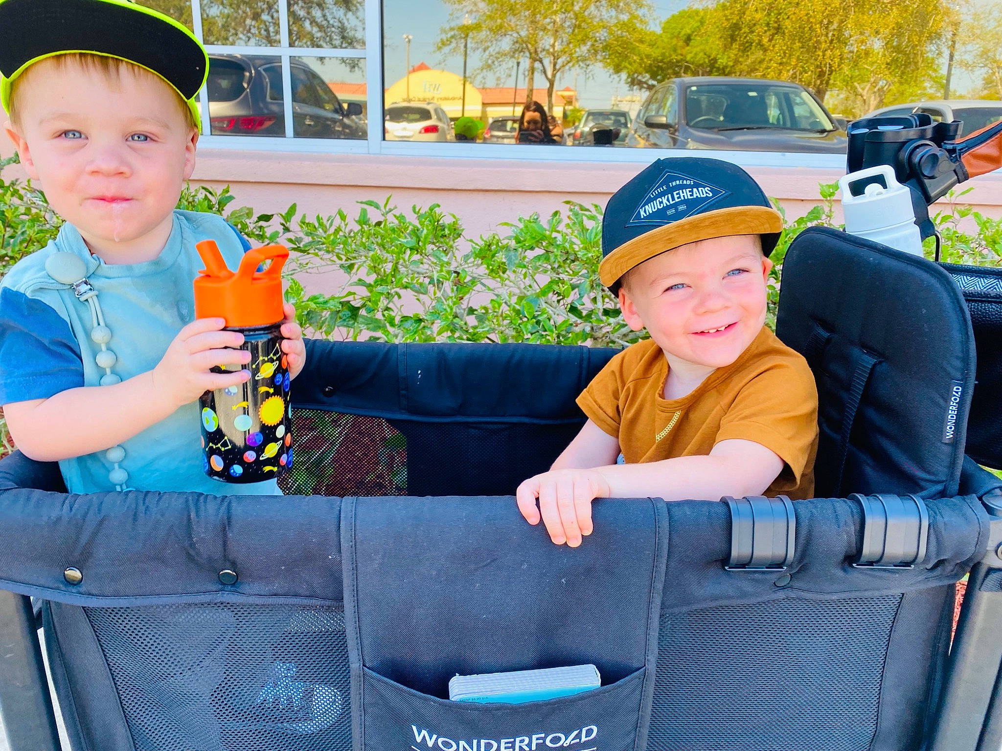 Miller is registered to the contest to win money with this photo: automotive_design, automotive_exterior, baseball_cap, cap, car, car_seat, child, comfort, face, fun, grass, headgear, headwear, joy, leisure, motor_vehicle, person, plant, smile, toddler
