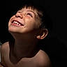 bare_shoulders, child, closeup, dark_background, emotion, expression, face, hair, happy, head, human, innocence, joy, light, looking_up, portrait, shadow, skin, smile, teeth