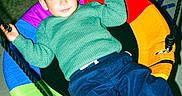 Thiago Alvarino is registered to the contest to win money with this photo: child, boy, swing, playground, colorful, green_sweater, blue_pants, white_shoes, grass, night, outdoor, play, rope, happy, casual_clothing, leisure, smile, fun, young, relaxed
