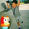 child, boy, bubbles, toy, bubble_blower, outdoor, backyard, happy, jumping, playful, concrete, sneakers, shorts, tshirt, hand, person, smiling, daylight, plastic_toy, summer