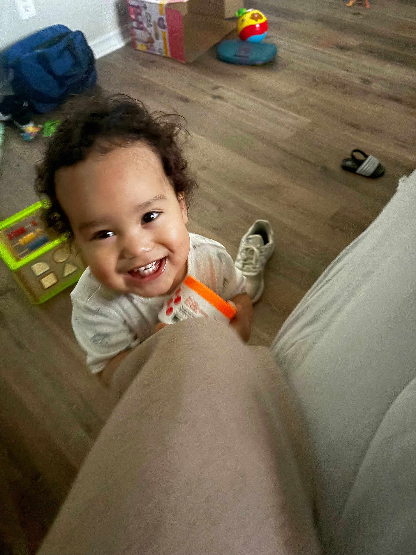 Esau joined the competition — help win amazing prizes! bright, candid, casual, child, clothing, container, curly_hair, floor, happy, holding, indoor, living_room, person, playful, shoe, smiling, toddler, toy, wooden_floor, young_child