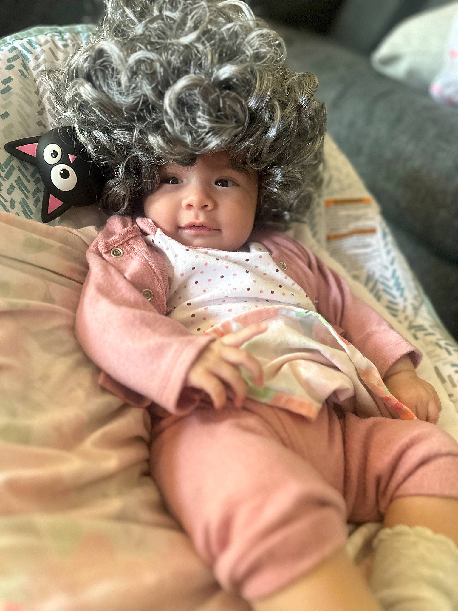 Daniela is registered to the contest to win money with this photo: abdomen, baby, baby_toddler_clothing, cheek, comfort, doll, eye, eyelash, fur, headwear, human_leg, linens, pattern, person, pink, sitting, skin, sleeve, thigh, toddler