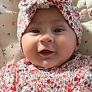 Jade a rejoint le concours — aidez-le/la à gagner de superbes lots ! baby, infant, face, headband, smile, blue_eyes, floral_pattern, clothing, cute, child, portrait, closeup, soft_lighting, indoors, bed, blanket, fabric, person, headwear, happy