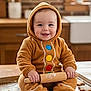 baby, infant, child, smiling, hooded_onesie, gingerbread_costume, rolling_pin, cookie_dough, cookies, baking, kitchen, wooden_countertop, flour, baking_sheet, cozy, portrait, cute, brick_wall, window, sink