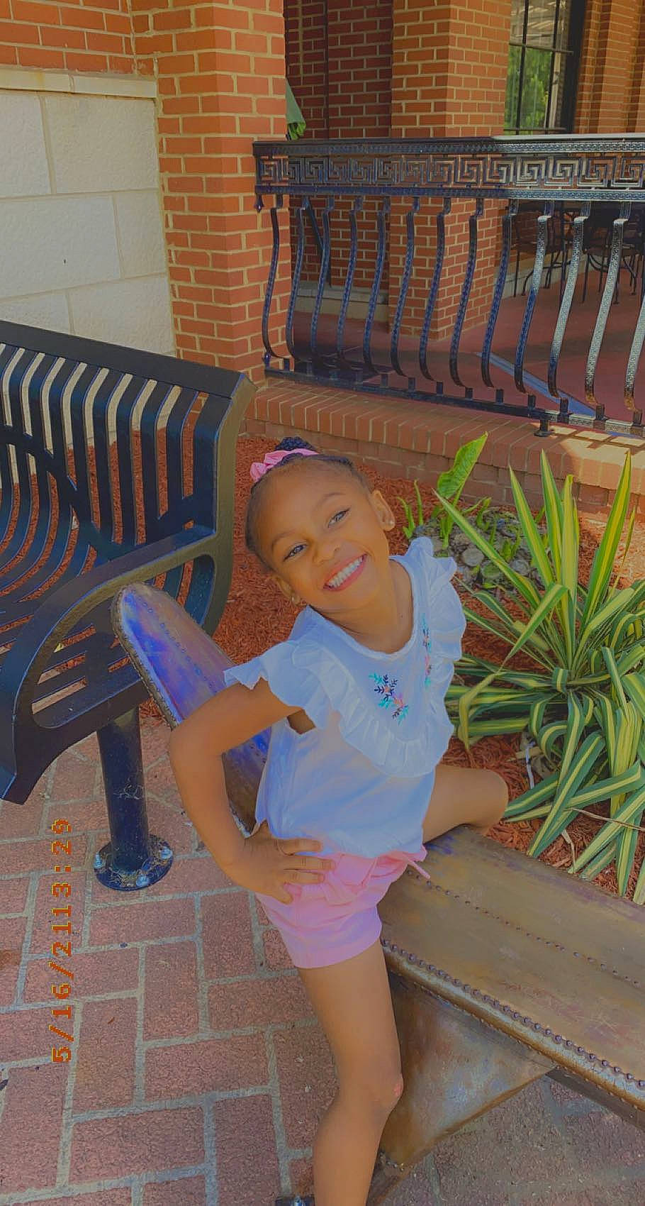 Maleah is registered to the contest to win money with this photo: barefoot, chair, electric_blue, flooring, foot, fun, furniture, happy, human_leg, joy, leg, leisure, organ, outdoor_furniture, person, plant, sandal, shorts, sitting, smile