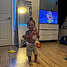toddler, child, barefoot, smiling, mirror, doll, bottle, wooden_floor, dresser, tv, cartoon, led_lights, room, door, window, curtains, toy, reflection, clothing, indoor