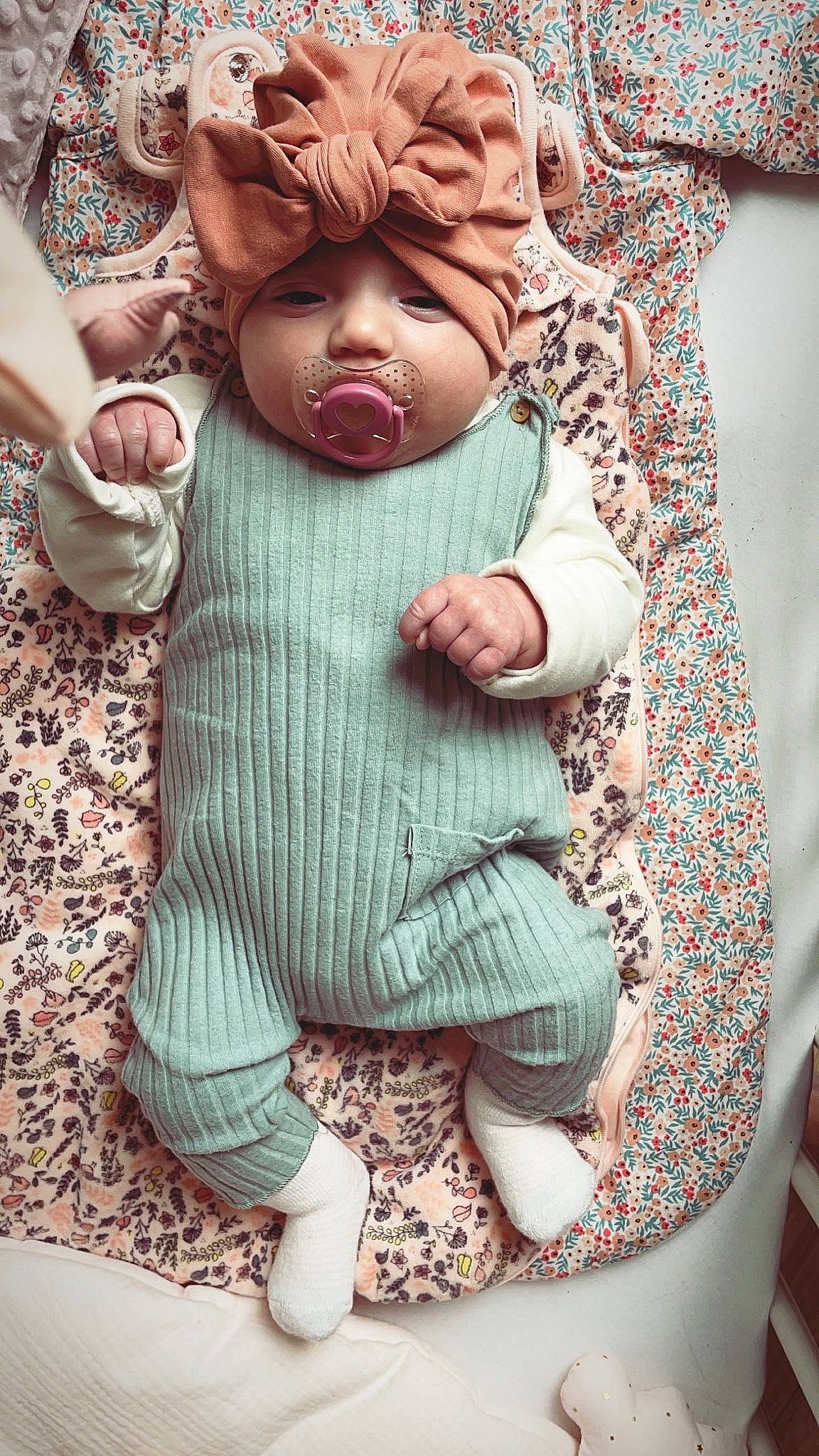 April participe au concours pour gagner de l'argent avec cette photo : art, baby, baby_toddler_clothing, child, doll, eyelash, finger, gesture, grey, hand, headwear, outerwear, pattern, person, pink, skin, sleeve, textile, thumb, toddler