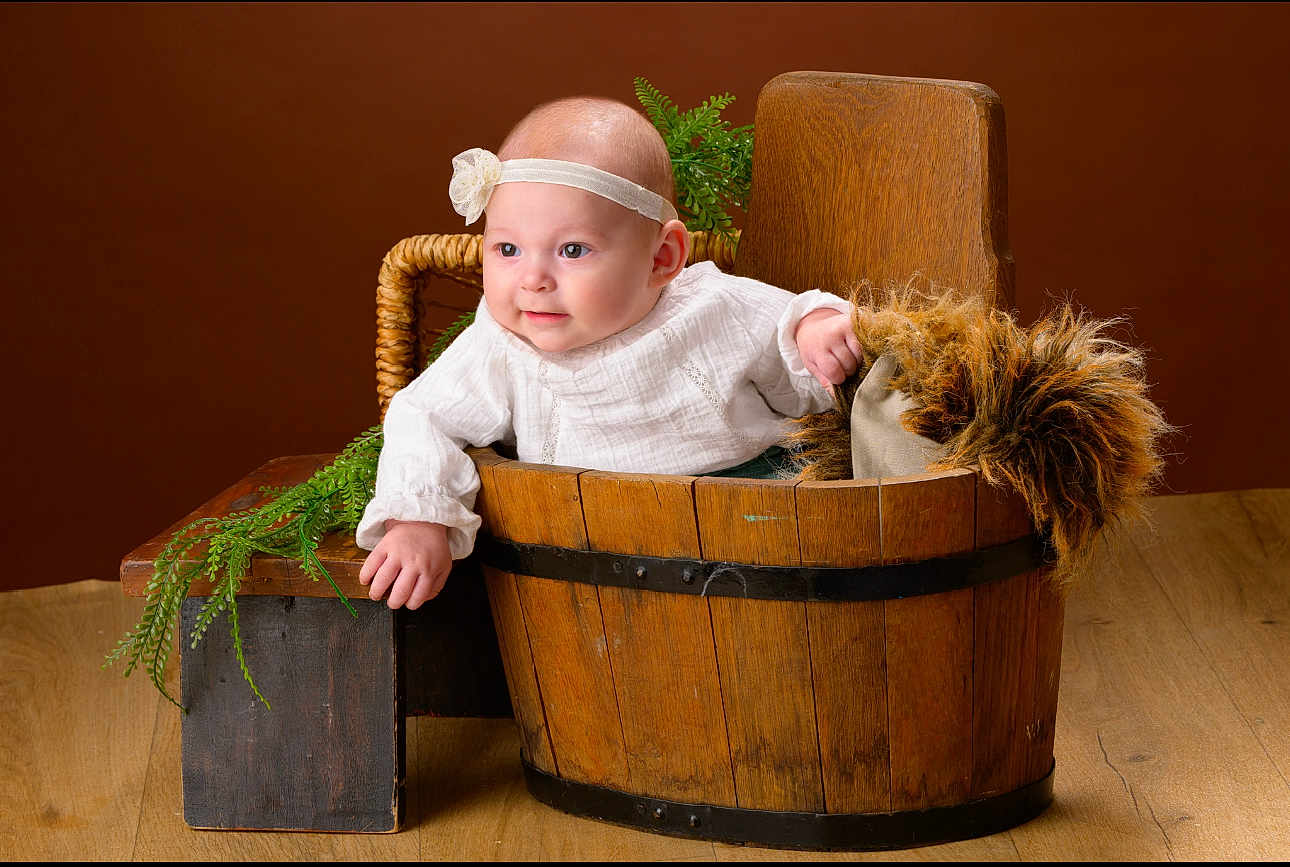 Nalya participe au concours pour gagner de l'argent avec cette photo : baby, infant, headband, wooden_bucket, bench, greenery, fur_pillow, white_outfit, portrait, studio, smile, chubby_cheeks, wooden_floor, prop, hand, eyes, cute, rustic, brown_background, basket