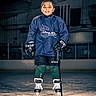 child, hockey_player, ice_skating, ice_rink, sports, athlete, portrait, smiling, helmetless, hockey_jersey, hockey_gloves, hockey_stick, skates, protective_gear, sports_uniform, ice, indoor, standing, young_athlete, action_sports