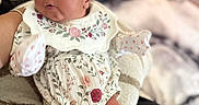 Serenity joined the competition — help win amazing prizes! baby, infant, child, portrait, sitting, floral_outfit, dress, bib, mittens, socks, flower, smiling, face, indoors, couch, blanket, armchair, home, soft_focus, photography