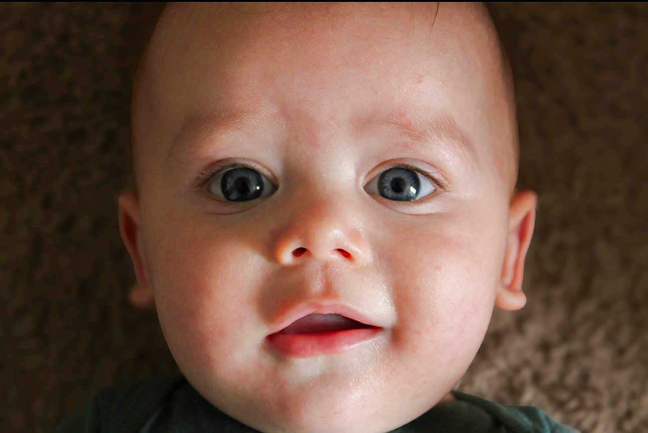 Cooper joined the competition — help win amazing prizes! baby, close_up, face, blue_eyes, infant, child, portrait, skin, expression, curious, soft_light, lying_down, head, mouth, person, young, innocence, background_blur, human, cute