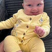 Olive joined the competition — help win amazing prizes! baby, child, smile, tongue_out, yellow_clothing, knitted, sitting, couch, happy, playful, indoor, person, cute, infant, portrait, face, hand, leg, sock, buttoned_cardigan