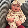 Olive is registered to the contest to win money with this photo: baby, child, smiling, headband, red_bows, cream_outfit, couch, texture, cozy, cute, rosy_cheeks, happy, portrait, indoor, person, seated, clothing, headwear, toddler, hands