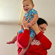 Sawyer is registered to the contest to win money with this photo: baby, child, person, indoor, smile, happy, lifting, blue_clothing, red_sweater, glasses, hand, foot, ceiling, playful, joyful, cute, holding, infant, family, casual