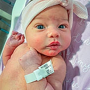 Remy is registered to the contest to win money with this photo: architecture, baby, bed, bodypart, bonnet, building, cap, clothing, face, finger, glove, hand, hat, head, hospital, newborn, person, photography, portrait, text