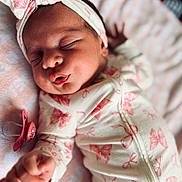 Vanessa is registered to the contest to win money with this photo: newborn, baby, sleeping, onesie, headband, pink, bow, pacifier, blanket, closeup, infant, peaceful, cute, soft, cozy, hand, face, clothing, portrait, indoor