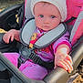 Charlotte is registered to the contest to win money with this photo: baby, child, stroller, hat, knit_hat, pink_clothing, outdoor, grass, seatbelt, hand, face, blue_eyes, person, infant, winter_clothing, cute, toddler, sunlight, daytime, portrait