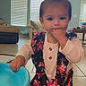 Skylar joined the competition — help win amazing prizes! toddler, child, indoor, floor, blue_object, hand_in_mouth, ponytail, floral_dress, long_sleeve_shirt, living_room, window_blinds, couch, table, tiles, cute, kneeling, home, baby, person, young_child