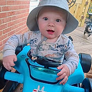 Mateo is registered to the contest to win money with this photo: baby, blue, brick_wall, child, clothing, decorative_star, dinosaur_print, dog, face, fence, hands, hat, outdoor, person, pet, portrait, smiling, steering_wheel, toy_car, wooden_deck