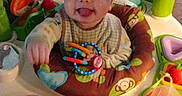 Mateo is registered to the contest to win money with this photo: activity_center, baby, child, clothing, colorful, cute, floor, fun, happy, indoor, infant, person, plastic, play, playtime, portrait, seat, smiling, tongue_out, toys