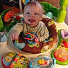 baby, smiling, tongue_out, activity_center, toys, colorful, indoor, child, play, seat, happy, person, infant, plastic, floor, clothing, playtime, cute, fun, portrait