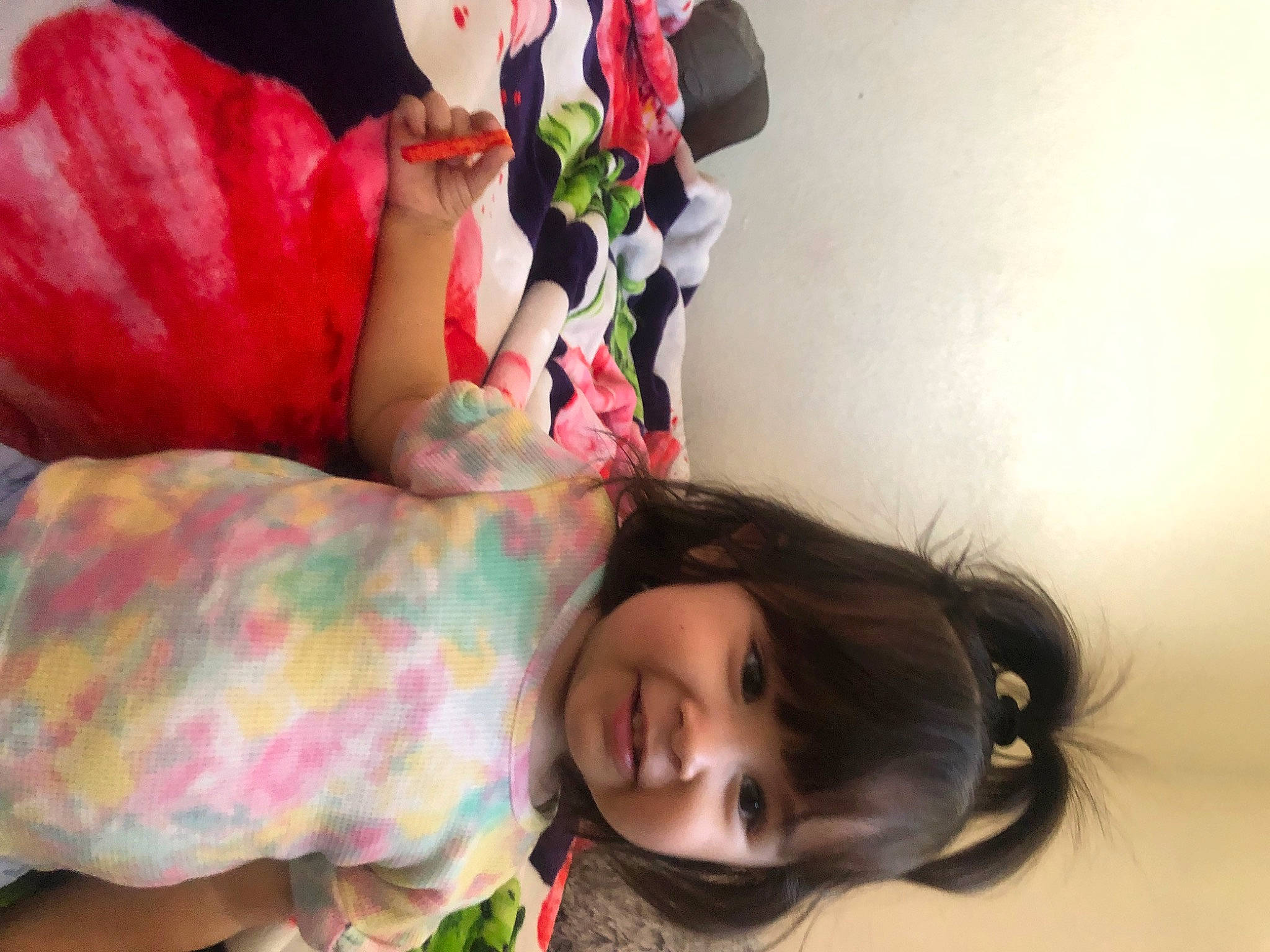 Bonnie is registered to the contest to win money with this photo: black_hair, child, clothing, comfort, dress, facial_expression, happy, human_leg, linens, lip, mouth, person, petal, pink, plant, skin, textile, toddler, toy, tree