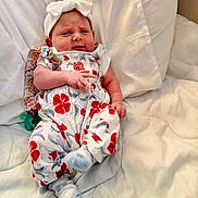 Aurora joined the competition — help win amazing prizes! baby, infant, headband, bow, floral_clothing, overalls, white_blanket, socks, indoors, cute, child, person, newborn, laying_down, portrait, soft_lighting, resting, expression, cozy, comfortable