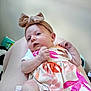 baby, infant, bow_headband, floral_dress, legs, skin, hand, face, person, clothing, indoor, cute, newborn, child, pink, orange, white, pattern, portrait, resting