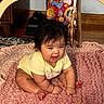 baby, child, yellow_onesie, pink_rug, indoor, wooden_furniture, toy, play_area, smiling, sitting, curious, floor, home, infant, cute, happy, person, soft_texture, decor, colorful