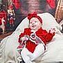 Elsie-Mae joined the competition — help win amazing prizes! baby, red_clothing, headband, blanket, christmas_stockings, nutcracker, holiday_decor, plaid_bow, white_tights, smiling, infant, festive, cozy, indoor, brick_wall_background, wooden_floor, toy_giraffe, snowshoes, portrait, cute
