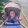 Elsie-Mae joined the competition — help win amazing prizes! baby, stroller, blanket, sidewalk, outdoor, sunlight, child, blue_eyes, happy, infant, clothing, person, road, vehicle, grass, daylight, transport, urban, smile, nature