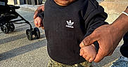 Akari is registered to the contest to win money with this photo: adidas, adult_hands, baby, black_sweatshirt, camo_pants, casual_clothing, child, curly_hair, cute, holding_hands, outdoor, person, portrait, sidewalk, sneakers, standing, stroller, sunlight, toddler, urban