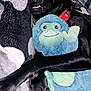 dog, black_dog, plush_toy, blue_toy, stuffed_animal, cuddling, blanket, patterned_blanket, collar, pet, indoor, paw, smiling_dog, flash_reflection, toy_monkey, lying_down, soft_texture, cute, animal, companion
