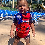 Damien joined the competition — help win amazing prizes! toddler, child, birthday_boy, red_outfit, racing_theme, blue_ribbon, poolside, lounge_chairs, water_slide, outdoor, sunny, smiling, happy, summer, footwear, shorts, standing, playground, trees, recreation