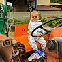 Michel a rejoint le concours — aidez-le/la à gagner de superbes lots ! child, toddler, tractor, orange, steering_wheel, seat, outdoor, farm, building, greenery, cloudy_sky, clothing, bib, shoes, smiling, person, rustic, metal, machine, agriculture