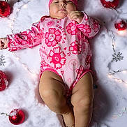 Emily joined the competition — help win amazing prizes! baby, infant, pink_clothing, onesie, hat, sleeping, snow_like_surface, christmas_ornaments, red_balls, fairy_lights, holiday_theme, cute, chubby_legs, peaceful, indoors, decorations, festive, soft_texture, child, person