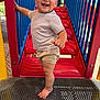 toddler, child, playground, smiling, barefoot, shorts, striped_shirt, red, blue, yellow, outdoor, daylight, happy, person, metal_platform, play_equipment, hand_rail, cute, skin, head