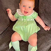 Isla-Rose joined the competition — help win amazing prizes! baby, child, red_hair, blue_eyes, green_dress, socks, bow, smiling, tongue_out, sitting, couch, indoor, cute, happy, infant, person, apparel, fabric, plush, comfortable