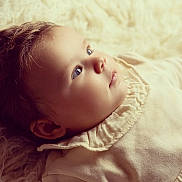 Mila a rejoint le concours — aidez-le/la à gagner de superbes lots ! baby, infant, face, portrait, soft_light, curly_hair, blue_eyes, clothing, fabric, texture, closeup, skin, cute, child, newborn, laying_down, peaceful, warm_tones, cozy, indoor