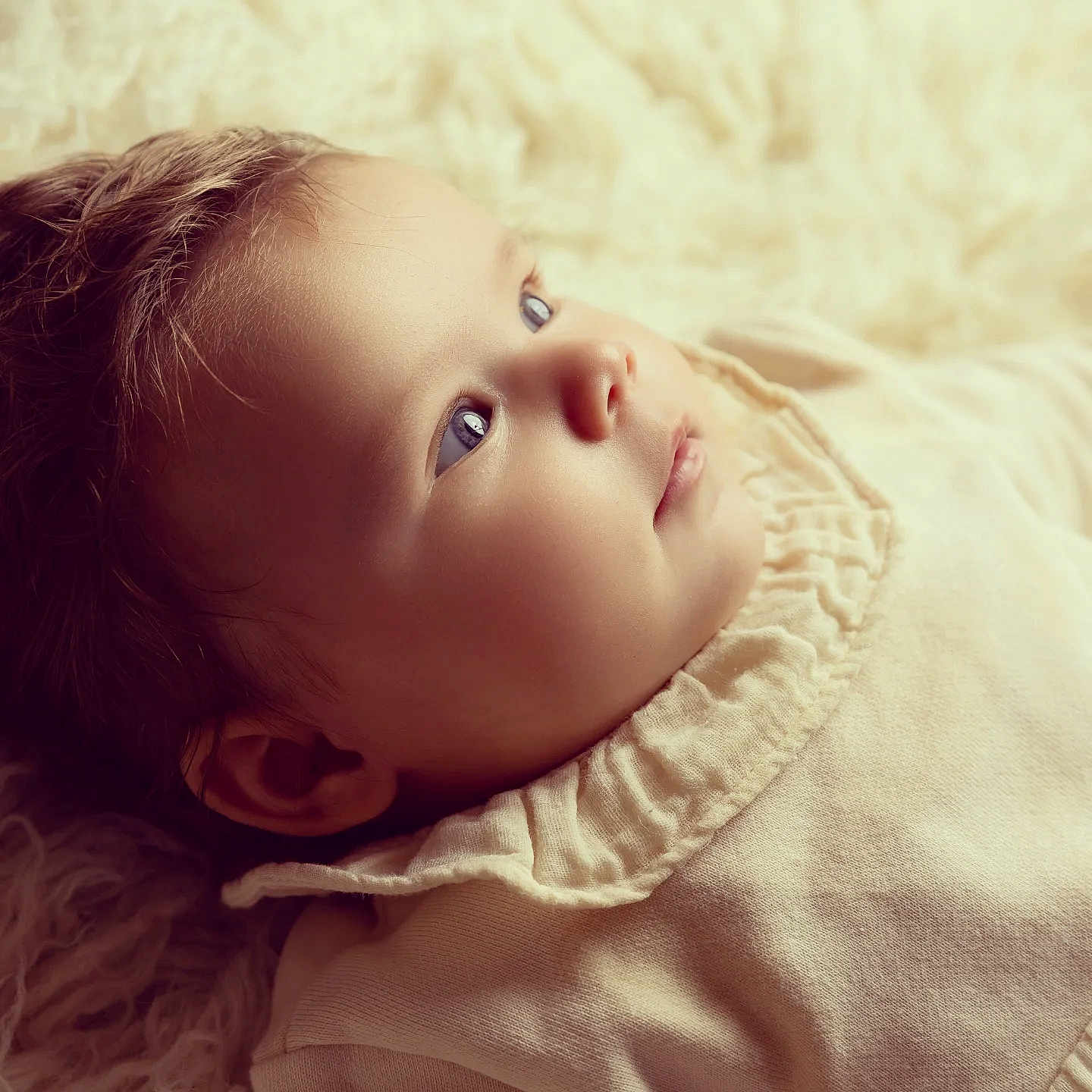 Mila a rejoint le concours — aidez-le/la à gagner de superbes lots ! baby, infant, face, portrait, soft_light, curly_hair, blue_eyes, clothing, fabric, texture, closeup, skin, cute, child, newborn, laying_down, peaceful, warm_tones, cozy, indoor