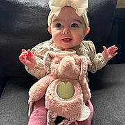 Sage joined the competition — help win amazing prizes! baby, child, bow, headband, plush_toy, elephant_toy, couch, pink_clothing, smiling, happy, indoors, cute, portrait, sitting, soft_toy, infant, hands, face, cozy, warm_lighting