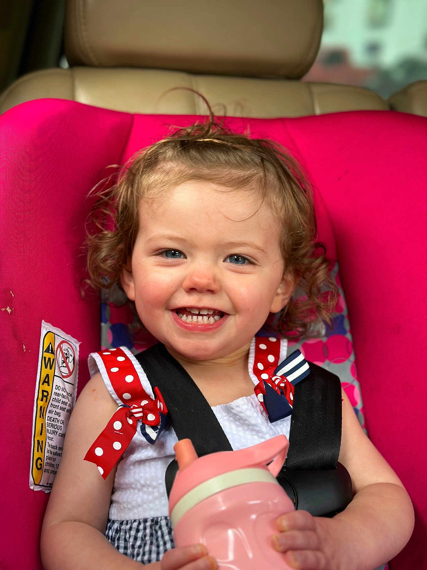 Addison joined the competition — help win amazing prizes! toddler, child, car_seat, pink, smiling, curly_hair, sippy_cup, seatbelt, red_bow, polka_dots, white_dress, happy, portrait, baby, cute, indoors, closeup, person, seat, safety